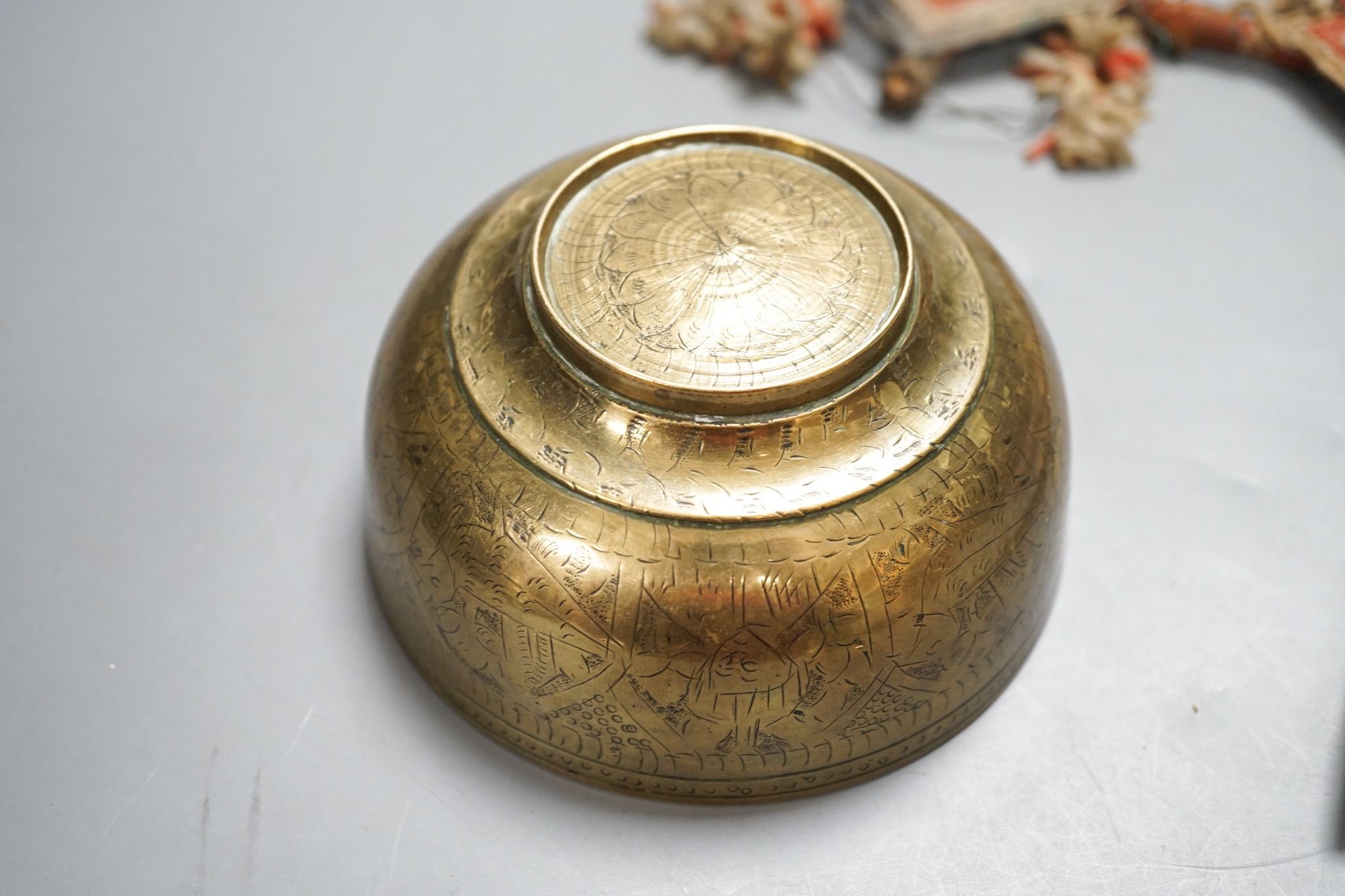 A Himalayan brass bell and bowl, a woolwork finial, 43 cm high, an Islamic tinned metal censer (4)